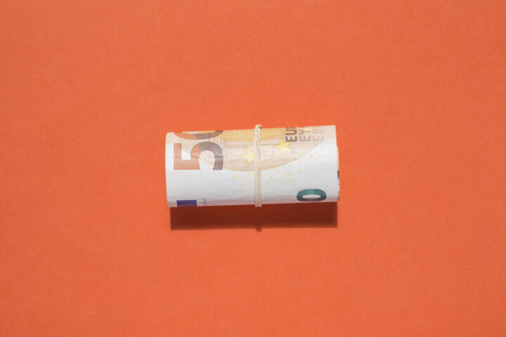 Billete de 50 euros atado con liga sobre fondo naranja
