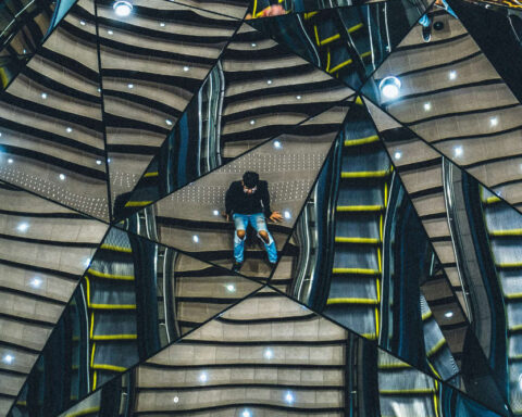 Persona reflejada en espejo fragmentado, distorsión de la relaidad, múltiples versiones de la realidad