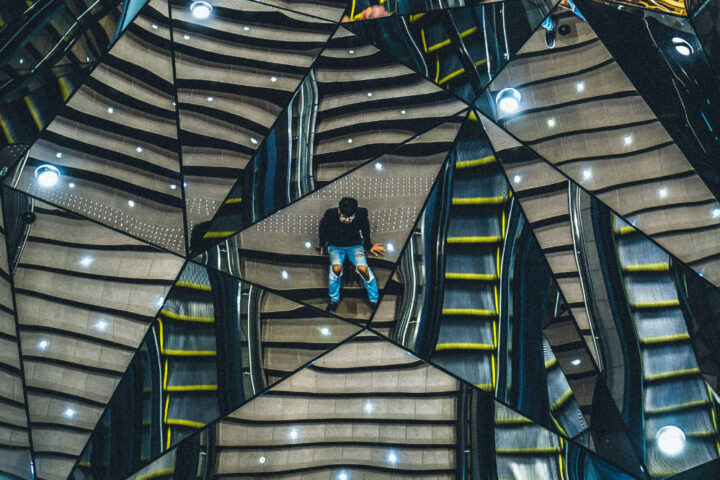 Persona reflejada en espejo fragmentado, distorsión de la relaidad, múltiples versiones de la realidad