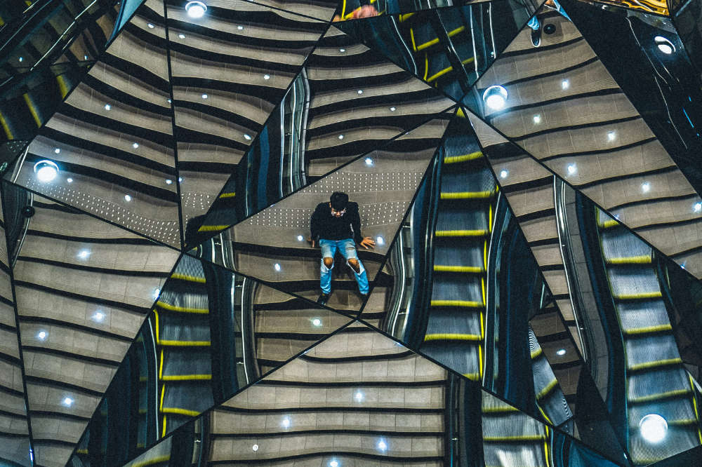 Persona reflejada en espejo fragmentado, distorsión de la relaidad, múltiples versiones de la realidad