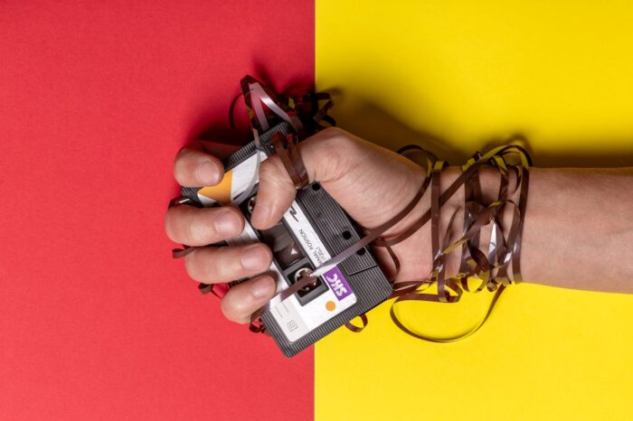 cassette de audio, y cinta enrededada en mano