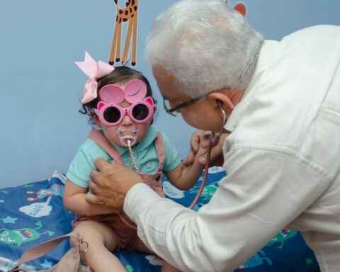 Médico examinando a una niña con estetoscopio en una consulta de pediatría y masculinidades.