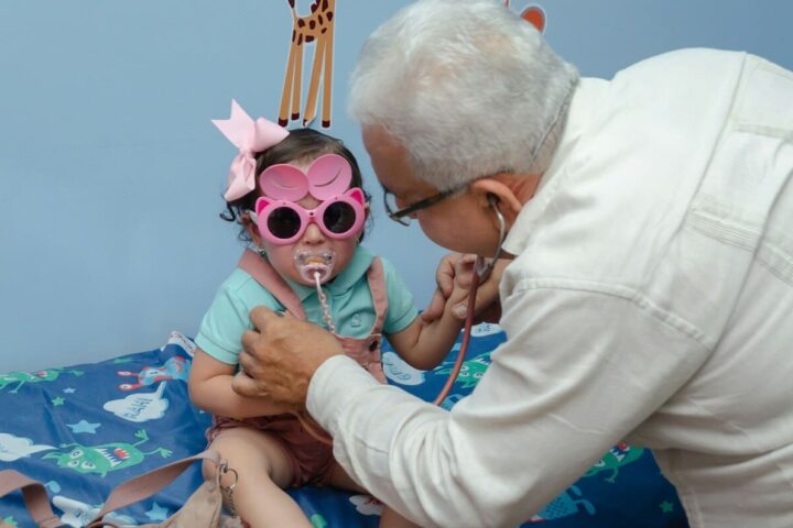 Médico examinando a una niña con estetoscopio en una consulta de pediatría y masculinidades.